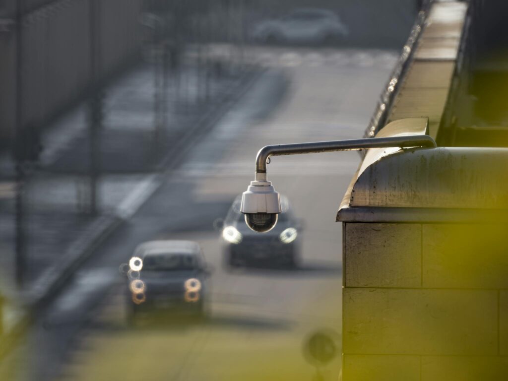 CCTV camera overlooking a busy street with cars in motion, capturing urban surveillance.